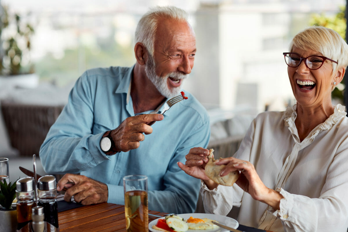 Senior living couple enjoying gourmet meal in independent restaurant.